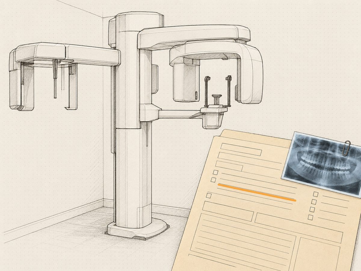 A panoramic x-ray unit standing in a small room, with a referral slip and one film clipped to it laid over the corner.